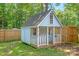A cute, little playhouse for children, nestled among trees in the backyard with decorative lighting and a porch at 318 W Peeler St, Salisbury, NC 28146