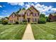 Classic brick home featuring manicured front yard with lush landscaping and a walkway to the front door at 4312 Beech Wood Ct # 140, Belmont, NC 28012