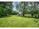Spacious backyard with a white storage building, mature trees, and lush green grass at 4720 Randleman Rd, Conover, NC 28613