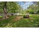 View of landscaped backyard with brick patio, waterfall feature, mature trees, and picnic table at 4720 Randleman Rd, Conover, NC 28613