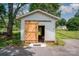 Exterior view of a white storage building with a natural-stained wooden barn door and concrete entryway at 4720 Randleman Rd, Conover, NC 28613