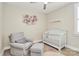 Charming Bedroom with white crib, comfortable gray chair and decorative flower wall art at 5129 Whitman Ave, Matthews, NC 28105
