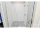 Sleek glass-enclosed shower with white tile walls and mosaic tile floor at 5129 Whitman Ave, Matthews, NC 28105