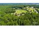 An aerial view of homes on lush green lawns surrounded by dense trees and a clear blue sky above at 5425 Creek Run Ct, Kings Mountain, NC 28086