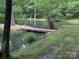 Picturesque pond featuring a rustic wooden bridge, enhancing its serene, natural ambiance at 5425 Creek Run Ct, Kings Mountain, NC 28086