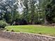 Sprawling backyard with lush green lawn, mature trees, playset, and retaining wall at 5916 Indian Brook Dr, Matthews, NC 28104