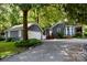 View of the home and detached garage showcasing the gravel drive, tree coverage, and cozy property at 5916 Indian Brook Dr, Matthews, NC 28104