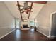 Spacious living room with exposed ceiling beams, hardwood flooring, and a traditional white fireplace at 5916 Indian Brook Dr, Matthews, NC 28104