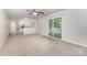 Spacious living room featuring neutral carpet, sliding glass doors, and view of an open kitchen through white decorative column at 7008 Wannamaker Ln, Charlotte, NC 28226