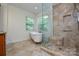 Bathroom featuring a glass-enclosed shower, clawfoot tub, and tile flooring, complemented by natural light from a window at 7321 Harrisonwoods Pl, Charlotte, NC 28270