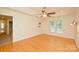 Bedroom featuring wood floors, a ceiling fan, and a view of a wooded backyard through two windows at 7321 Harrisonwoods Pl, Charlotte, NC 28270