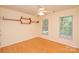 Bright bedroom with hardwood floors, modern track lighting, two windows, and custom wall-mounted shelving at 7321 Harrisonwoods Pl, Charlotte, NC 28270