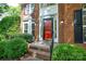 Inviting brick home entrance featuring a red door, decorative windows, and manicured greenery at 7321 Harrisonwoods Pl, Charlotte, NC 28270