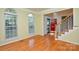 Sunlit living room with hardwood floors, large windows, and a view of the entry and staircase at 7321 Harrisonwoods Pl, Charlotte, NC 28270