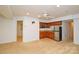 Living room area with kitchenette featuring stainless steel refrigerator, wood cabinets, and granite countertops at 7321 Harrisonwoods Pl, Charlotte, NC 28270