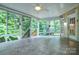 Bright sunroom featuring tile flooring, ceiling fan, and sliding glass windows with a view of the wooded backyard at 7321 Harrisonwoods Pl, Charlotte, NC 28270