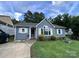 Charming one-story home with a well-manicured lawn, inviting entry and mature trees in the background at 7401 Merrily Ln, Charlotte, NC 28214