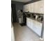 Galley kitchen with white cabinets, stainless steel appliances, mosaic backsplash, and tile floors at 7401 Merrily Ln, Charlotte, NC 28214