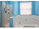 Bright blue bathroom features shower, large tub, and window for natural light at 8002 Kingston Dr, Waxhaw, NC 28173