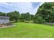 The backyard features a lush lawn, mature trees, and a patio set for outdoor entertaining at 8904 Gerald Dr, Charlotte, NC 28217