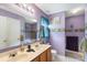 Bright purple bathroom featuring dual sinks, a large mirror, and tub at 8904 Gerald Dr, Charlotte, NC 28217