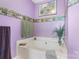 Large soaking tub in the purple bathroom with decor and plant at 8904 Gerald Dr, Charlotte, NC 28217