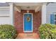 Close-up of a charming blue front door with a wreath, brick surround, and neatly trimmed bushes at 8904 Gerald Dr, Charlotte, NC 28217