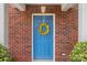 Close-up of a charming blue front door with a wreath and brick surround at 8904 Gerald Dr, Charlotte, NC 28217
