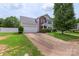 View of home with light grey siding, brick facade, blue shutters, a 2-car garage, and a long driveway at 8904 Gerald Dr, Charlotte, NC 28217