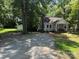 Inviting one-story home featuring a cozy front porch and a spacious gravel driveway surrounded by mature trees at 917 Tennyson Dr, Charlotte, NC 28208
