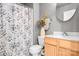 Bathroom with gray accent wall, wood vanity, and shower with patterned curtain at 9716 Psalms St, Cornelius, NC 28031