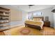 Bright bedroom featuring hardwood floors, large window, and wooden headboard at 1011 Westbrook Dr # A, Charlotte, NC 28202