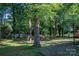 Landscaped backyard with mature trees and partial hardscape for patio at 10925 Lassen Ct, Charlotte, NC 28214