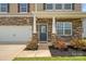 Close up of a charming home featuring stone accents, a two-car garage, and a well-manicured front lawn at 128 Cherry Birch St, Mooresville, NC 28117
