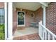 Inviting front porch with brick columns, a decorative wreath on the front door, and seating for relaxing outdoors at 1308 Stonewyck Dr, Salisbury, NC 28146