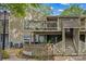 Two-story home with wood siding, balcony, stairs, and brick landscape feature at 1604 Sharon W Rd, Charlotte, NC 28210