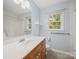 Bright bathroom featuring a wooden vanity, white countertop, and natural light from the window at 2020 Dawnshire Dr, Gastonia, NC 28054