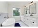 Bright bathroom featuring a soaking tub, modern fixtures, double vanity, and a large window at 2333 Greenland Ave, Charlotte, NC 28208