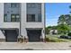 Street view of the townhome garages, featuring gray doors, stone accents, and freshly landscaped yard at 2969 Simpson Dr, Charlotte, NC 28205