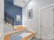 Hallway with light blue walls, modern art, hardwood stairs with black railing, and striking blue accent wall at 327 S Turner Ave, Charlotte, NC 28208