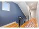 Well-lit hallway with hardwood floors, a modern railing, and a vibrant blue accent wall at 327 S Turner Ave, Charlotte, NC 28208