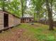 Expansive backyard featuring an log cabin house, outdoor firepit, mature trees and a storage shed at 5109 Walnut Grove Ln, Charlotte, NC 28227