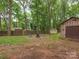 Spacious backyard with a storage shed, fire pit, and wooden fence surrounded by beautiful, mature trees at 5109 Walnut Grove Ln, Charlotte, NC 28227