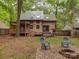 View of the back of a log cabin style house with a deck, hot tub, fire pit, and lush trees at 5109 Walnut Grove Ln, Charlotte, NC 28227