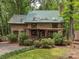 Charming log cabin featuring a metal roof, stone chimney, and cozy front porch at 5109 Walnut Grove Ln, Charlotte, NC 28227