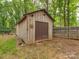 A wooden storage shed with double doors and a decorative sunburst, nestled in a wooded backyard at 5109 Walnut Grove Ln, Charlotte, NC 28227