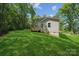 A spacious backyard with green grass, a deck, and a house nestled among lush trees at 54 Reed Ne St, Concord, NC 28025