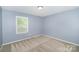 Well-lit bedroom with a large window and neutral carpet at 6300 Morehead Rd, Harrisburg, NC 28075