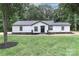 Beautiful house with black roof and white siding and black trim sits on a large grassy yard with trees at 6310 Forney Hill Rd, Denver, NC 28037