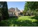 Expansive backyard with a well-maintained lawn, mature trees, and a view of the home's exterior at 6507 Fairway Point Dr, Charlotte, NC 28269